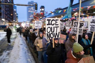Protesters march Tuesday while holding signs that read 'ICE out now' in Minneapolis